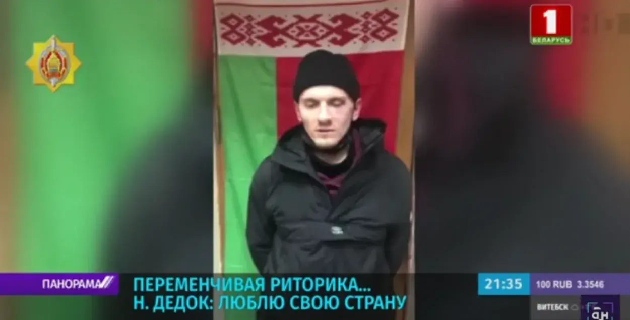 Николай Дедок после задержания на фоне красно-зелёного флага / Скриншот с видео, показанного на телеканале "Беларусь 1"​